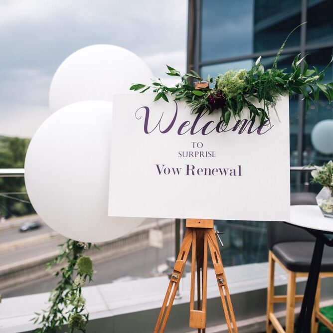 Closeup of easel with white Welcome sign on frame stands on the roof top during wedding party. Vow renewal